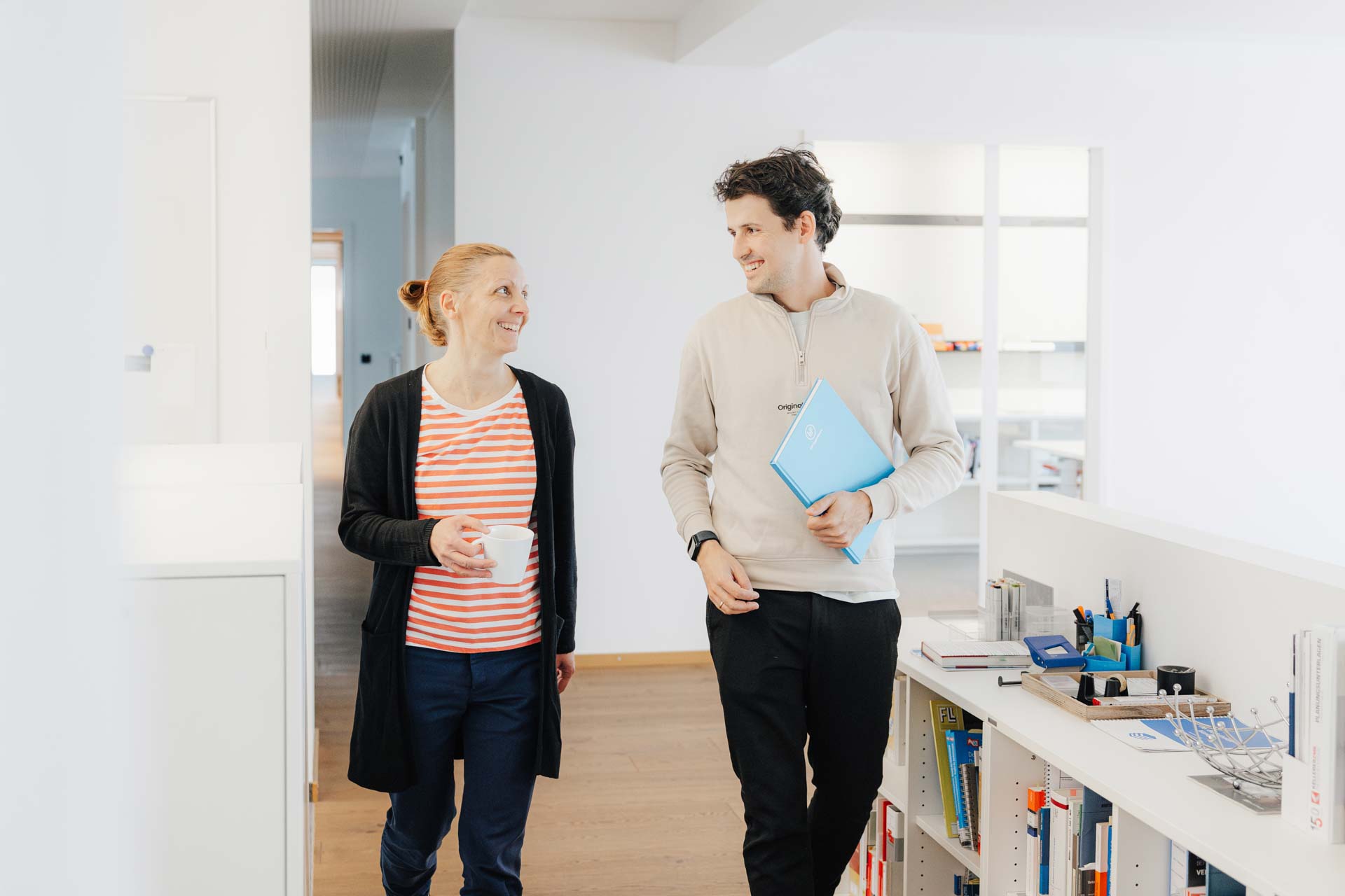 Mitarbeiterin und Mitarbeiter im Flur auf dem Weg zu einem Termin.